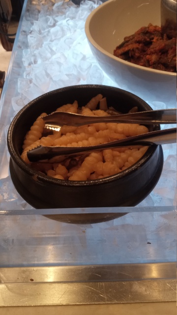 A black
bowl of pale-colored things that strongly resemble large grubs.  Each
grublike thing is tapered at the ends, a few centimeters long and
about one centimeter thick in the middle.  Each one is shaped like a
stack of tires or M&M candies, but not colorful. They are presented in
a dark earthenware bowl on a bed of ice, with a pair of tongs.