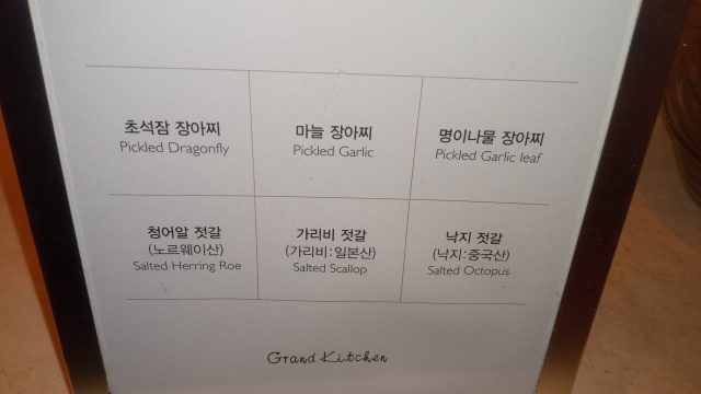 Photograph
of sign from the buffet, describing six available side dishes in
English and Korean: “Pickled Dragonfly”, “Pickled Garlic”, “Pickled
Garlic Leaf”, “Salted Herring Roe”, “Salted Scallop”, and “Salted
Octopus”.