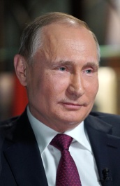 Putin in 2018 is 66 years old but
looks much younger. He has a round face, a calm and thoughtful expression, and cold blue eyes.  His hair,
medium-brown and thinning, is gray only at the temples. He wears a
dark suit jacket, white shirt, and a dark red silk tie in a striking pattern.