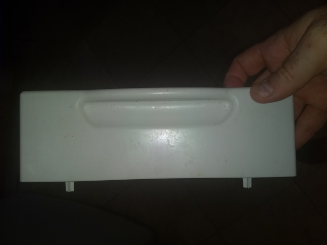 A photograph of my hand, holding rectangular piece of white
plastic with a handle-shaped indentation on the front and two short
feet sticking out below