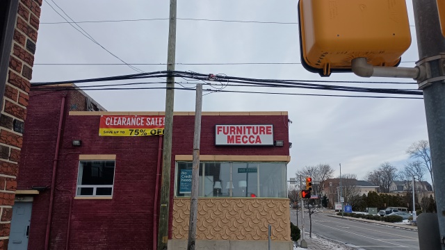 Photograph of a
Philadelphia furniture store named Furniture Mecca.  A Red and yellow
sign announces 'Clearance Sale!  Up to 75% off;