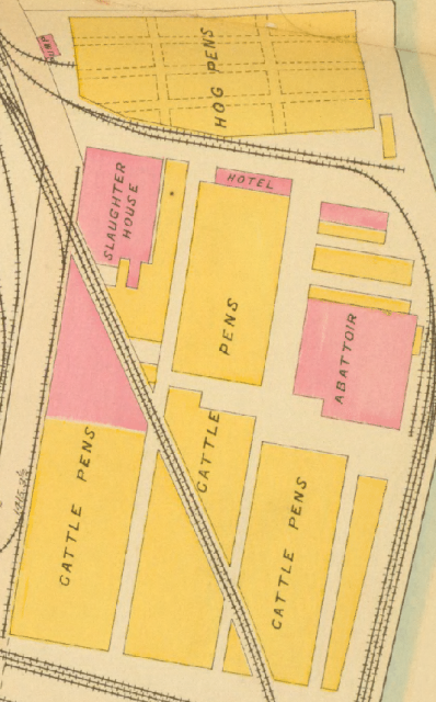 A portion of a map, with buildings
marked in yellow and pink.  Several large yellow buildings, surrounded
and cut through with rail lines, are labeled CATTLE PENS.  Pink
buildings on the left and right are SLAUGHTER HOUSE and ABBATOIR.  In
between is a smaller pink building labeled HOTEL.  Just north of the
hotel are the HOG PENS.