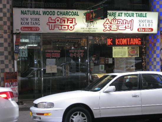 The storefront of a New York restaurant. It has a white sign with
English 'NATURAL WOOD CHARCOAL PREPARE AT YOUR TABLE' in green, and
Korean 'Nyuyeok gomtang sootbool galbi' in red Hangul script