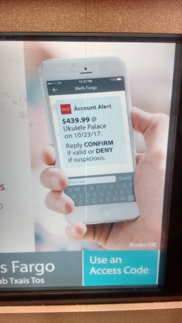 A phone displaying a
Wells Fargo 'Account Alert' about a charge of $439.99 at 'Ukulele Palace'