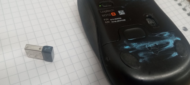 Logitech mouse, lying on its
back, and its dongle.  The head of the dongle and the underside of
the mouse have been scribbled on with sky-blue
paint.