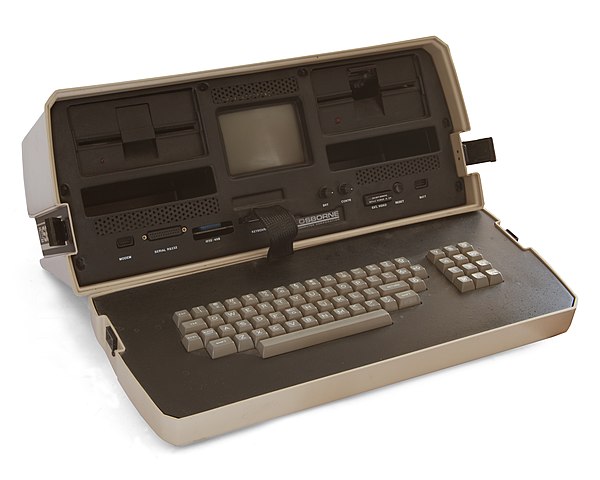 The Osborne
1 is a beige box the size of a toolbox.  Its lid conceals a full-sized
keyboard attached to the rest of the box by a ribbon cable.  Packed
into the box are a very small CRT monitor, two 5¼ inch diskette
drives, assorted I/O receptacles, and, not visible, the computer
itself.
